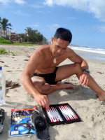 Kelvin entertains himself with a backgammon board and the latest copy of Scientific American! New Year's Day, Playa El Agua, Margarita Island, Venezuela